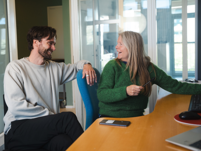 To kollegaer i en samtale foran en computer i personalerummet