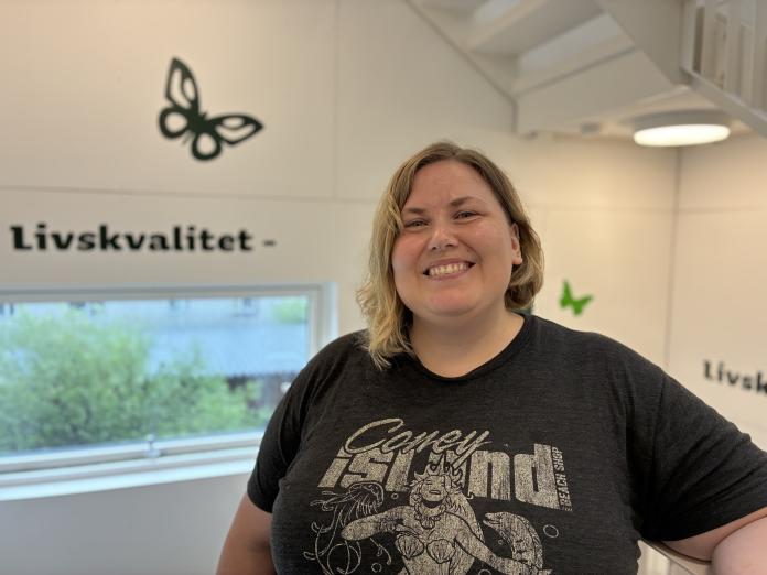 Emma-Rose, socialpædagog på Grøndalsvænge, står i trappeopgang. I baggrunden ses teksten "Livskvalitet" på væggen.